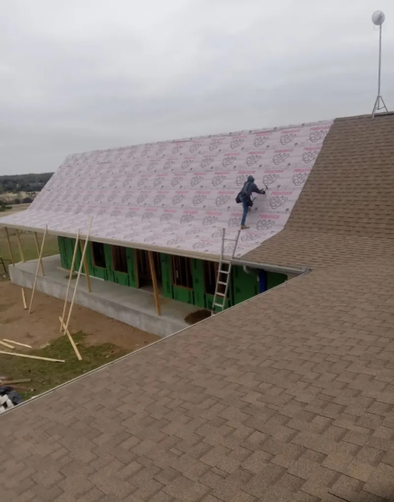 Worker preparing underlayment for a metal roof installation in Courtland